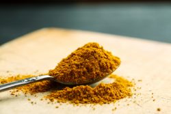 A picture of a heaping spoonful of turmeric powder